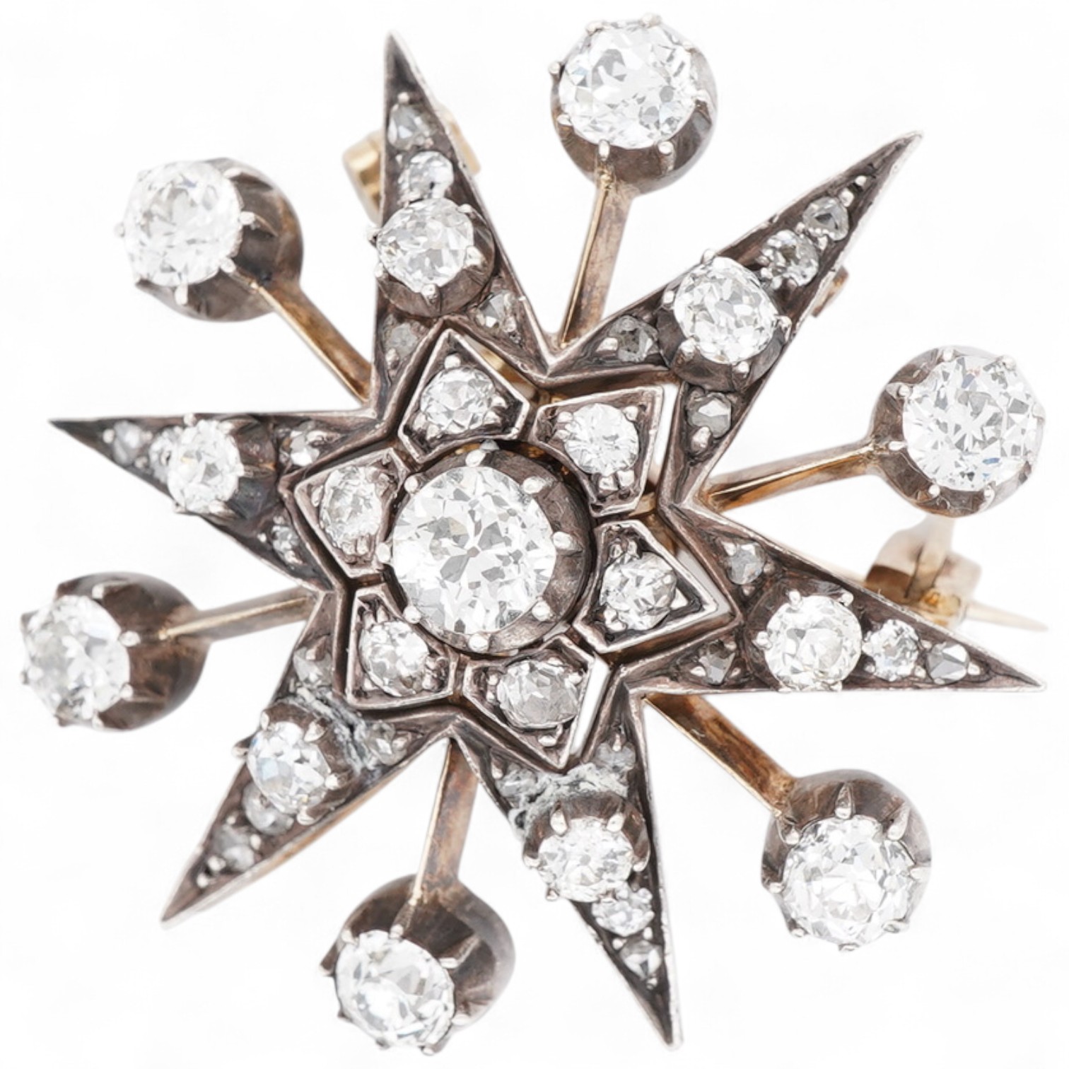 A Victorian diamond brooch/pendant, late 19th century, designed as a star, set with circular-cut, cushion-shaped and rose-cut diamonds totalling approximately 1.80 carats, mounted in silver and gold, length 3cm, gross we